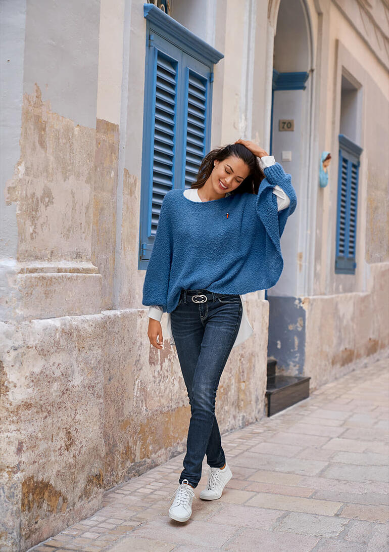 Blau Frau trägt blauen Bouclé-Poncho-Pullover in einer Altstadtgasse