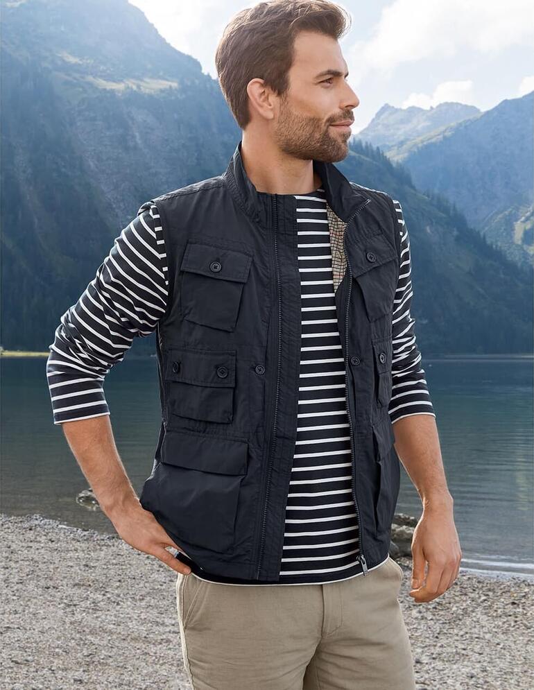 Mann in schwarzer 10-Taschen-Weste schaut auf einen Bergsee.