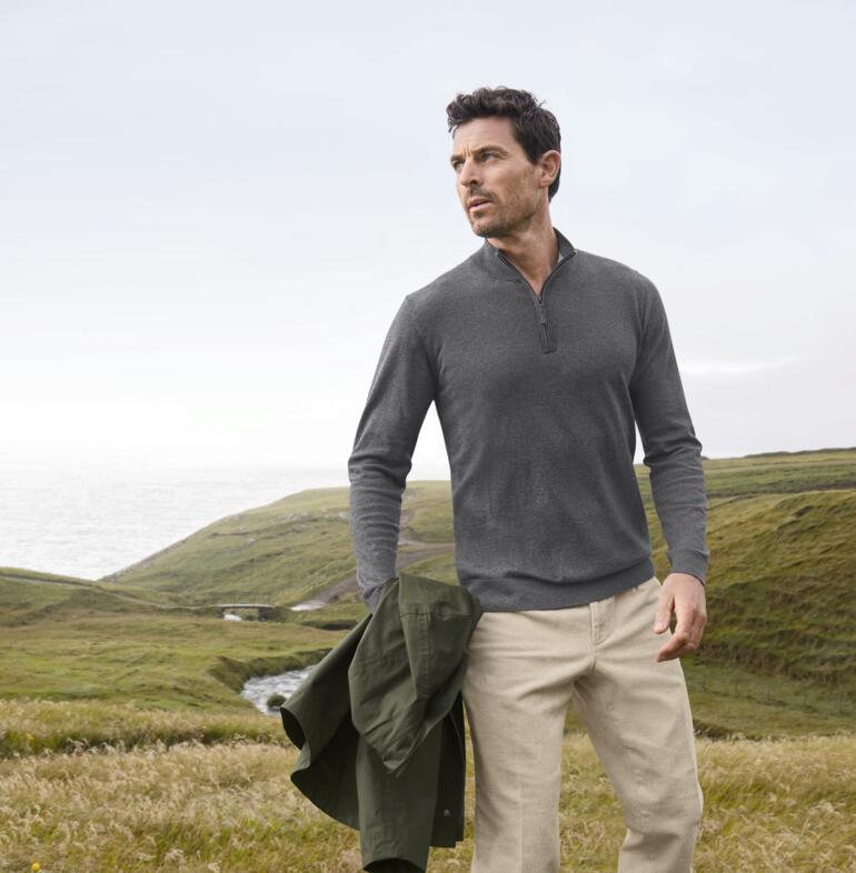 Mann trägt grauen Alan Paine Ganzjahres-Troyer mit einem Ort im Hintergrund.