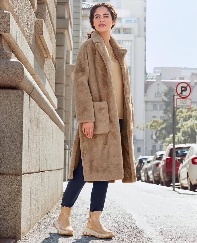 Sand Frau in einer beigen Jacke und Chelsea-Sneakerboots auf der Straße