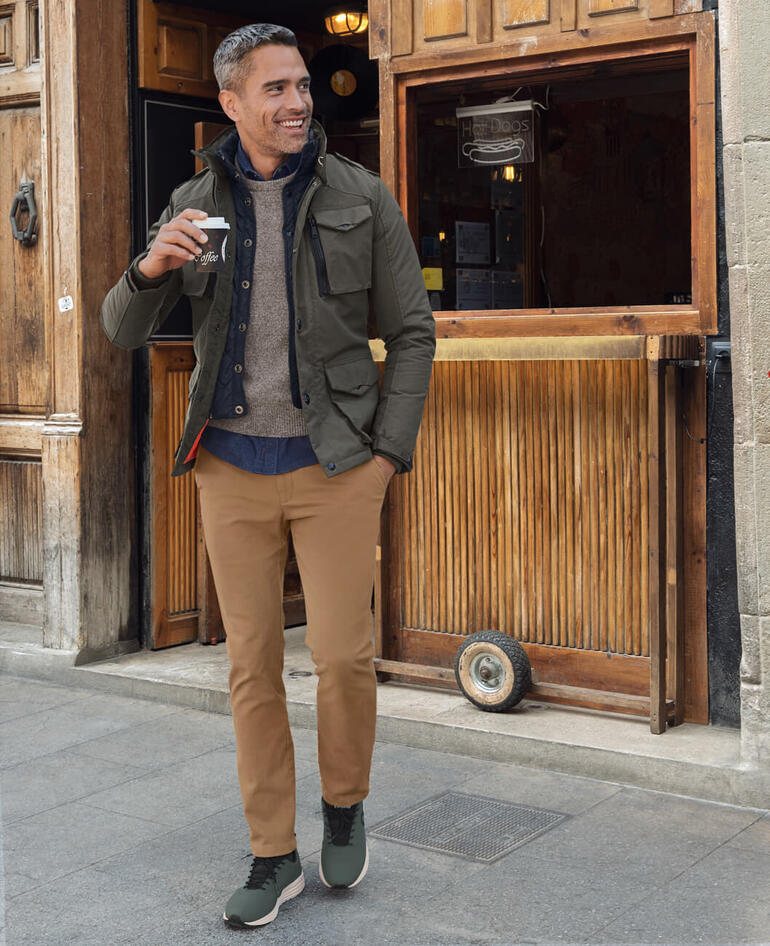 Schott NYC Nylon-Canvas-Fieldjacket Mann in nachhaltigen Sneakers, trägt einen Kaffee.