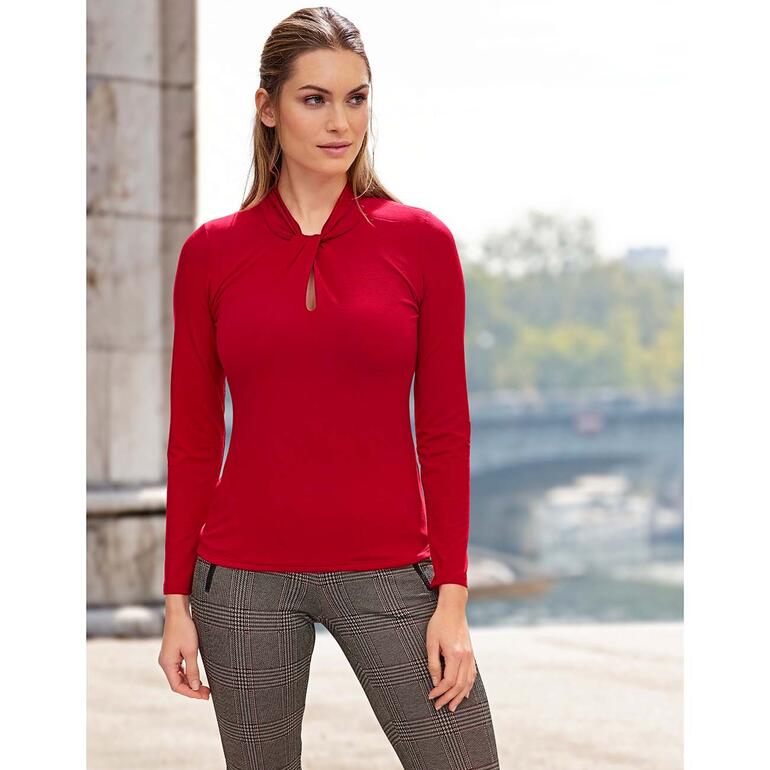 Rot Frau in rotem Tencel-Shirt mit Schlüsselhalsschlitz vor urbanem Hintergrund.