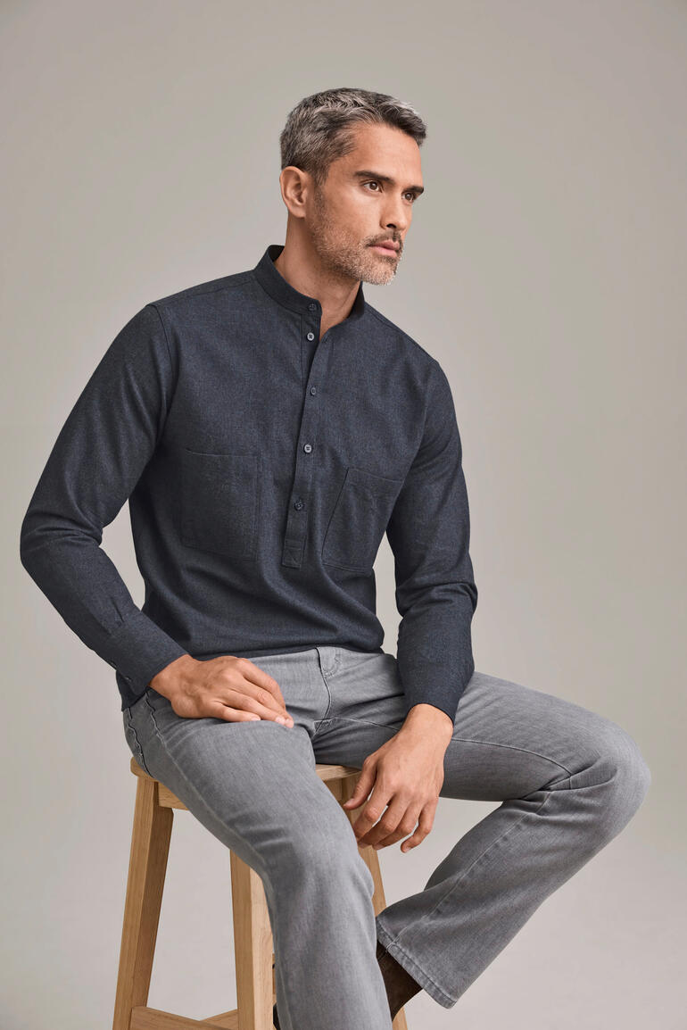 Mann in Nehru-Hemd aus Baumwolle-Flanell in Dunkelgrau sitzt auf einem Stuhl.