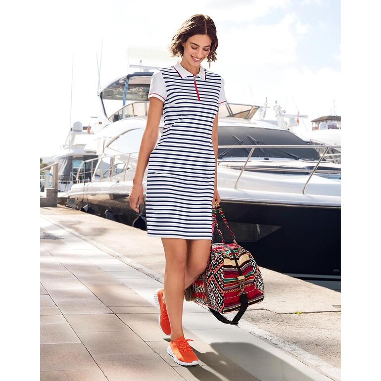 Orange Frau im gestreiften Polokleid von Saint James, geht am Hafen mit Tasche.