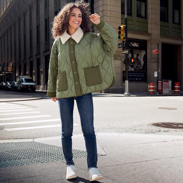 WOMSH Vintage-Sneaker Frau trägt Vintage-Sneaker mit heller Jacke auf der Straße.