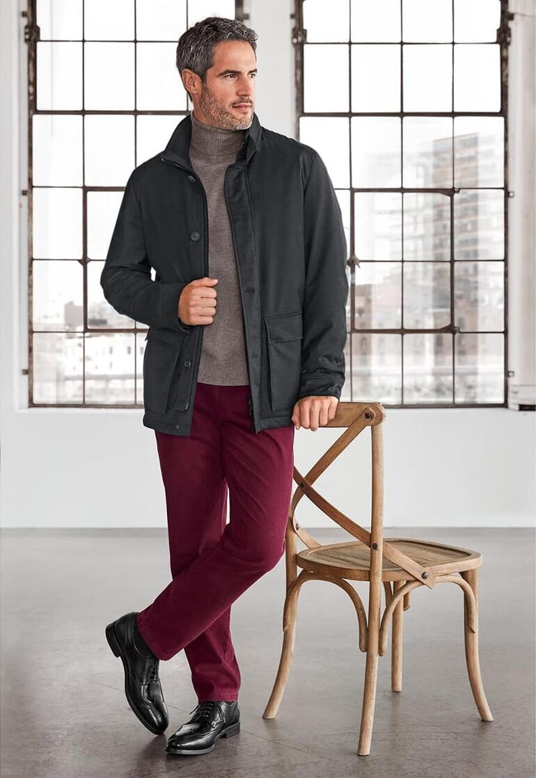 Mann in Schneiders Storm-System®-Jacke steht vor einem Fenster in moderner Umgebung.