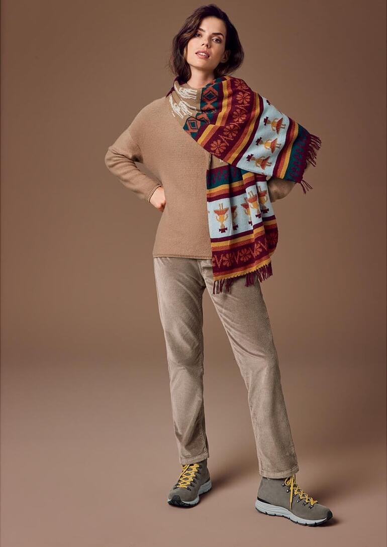 Taupe Frau trägt handgestrickten Alpaka-Schal mit beige Pullover und Jogginghose.
