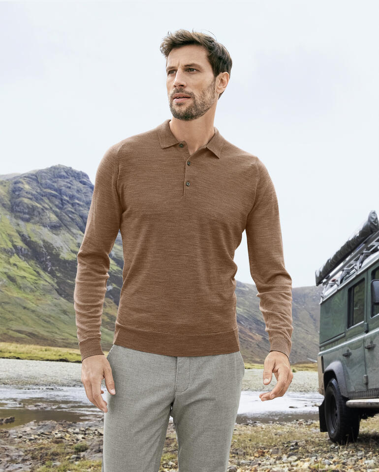 Ginger Mann trägt ein Langarm-Polo von John Smedley in Ginger-Farbe in der Natur.