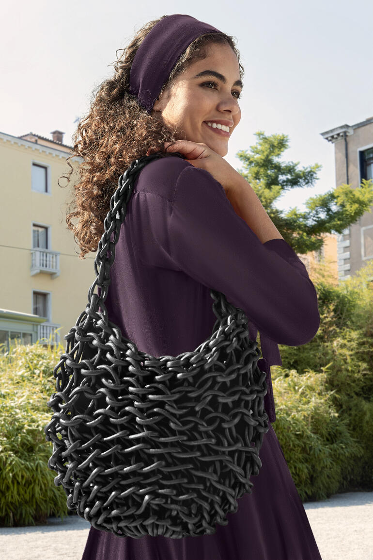 Schwarz Glänzende schwarze Flechtasche Alienina, von einer Frau getragen.