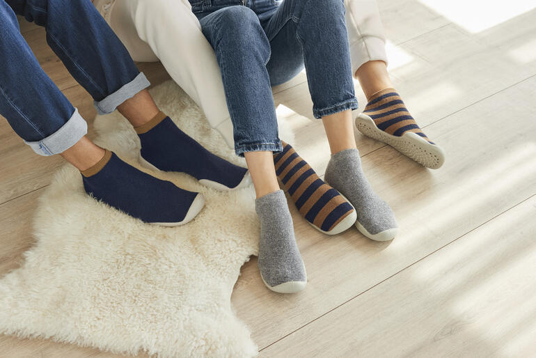 Haussocken in Navy, Grau und gestreift, auf einem hellen Boden.