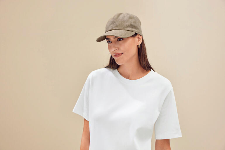 Sand Frau in hellem T-Shirt trägt Basecap und lächelt.
