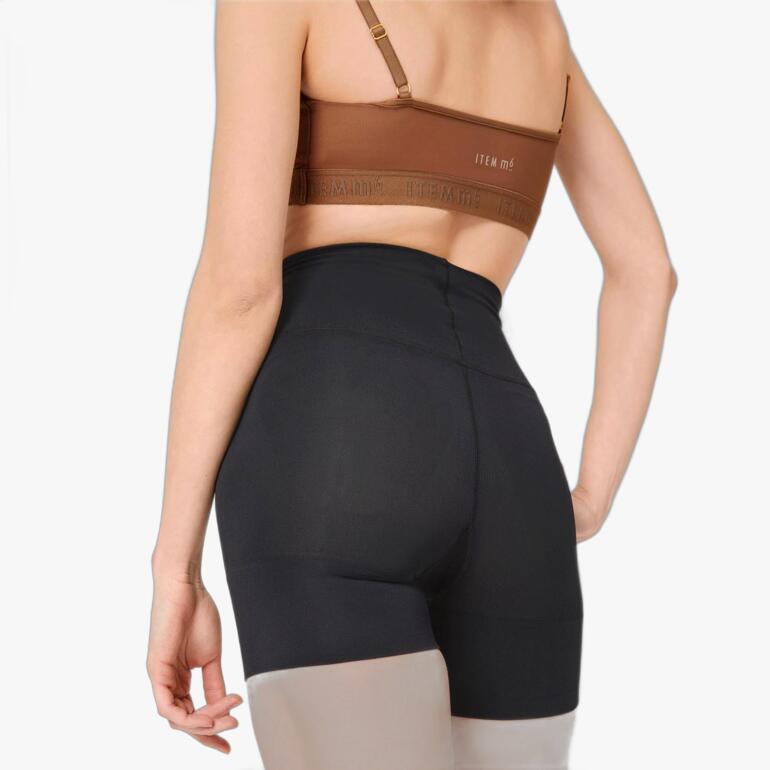 Frau in schwarzen Item m6 Shape-Shorts, von hinten betrachtet.