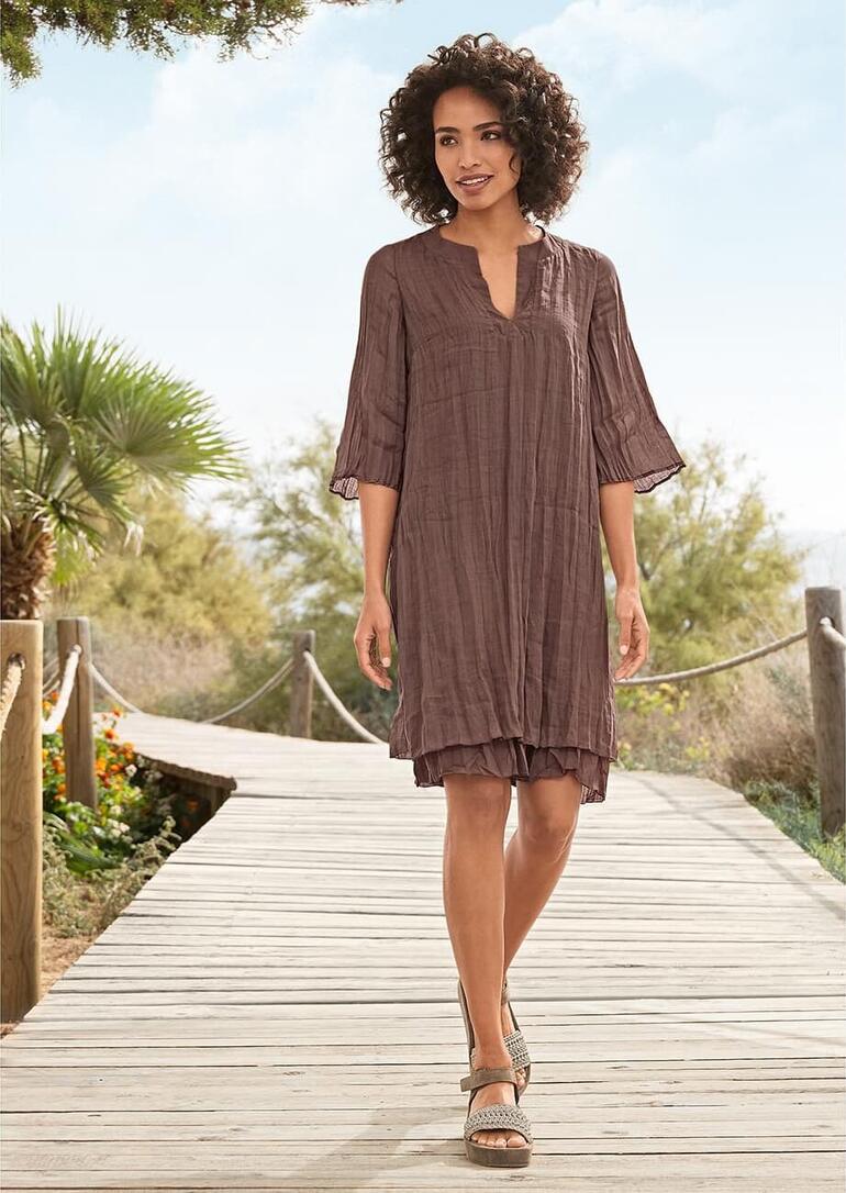 European Culture Layering-Kleid Frau im Chocolate Layering-Kleid auf einem Holzsteg.
