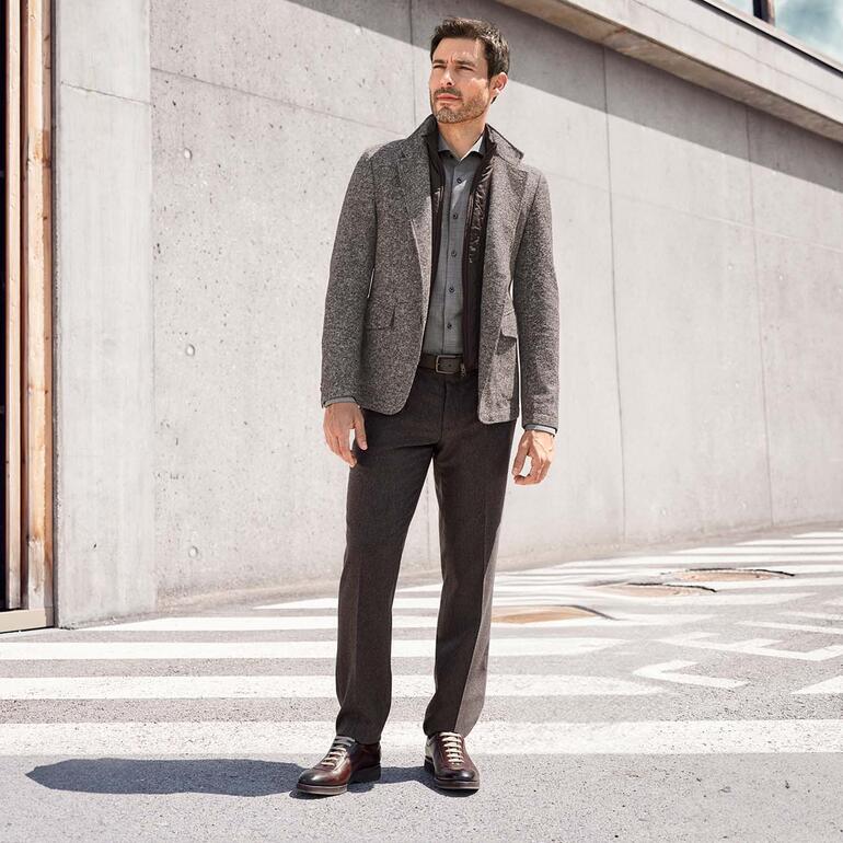 Braun Mann in grauer Kaschmir-Wollhose und Jacke, posierend auf Betonstraße.
