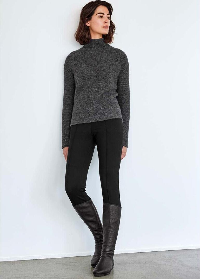 Grau Frau trägt grauen Boxy-Pullover und schwarze Leggings.
