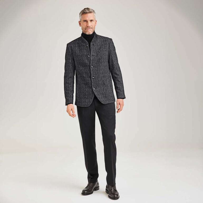 Hirschleder-Business-Schuh Mann in schwarzem Outfit mit Leder-Business-Schuhen, steht auf neutralem Hintergrund.