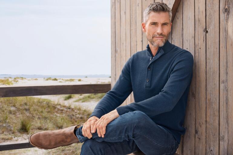 Mann in marineblauem Troyer mit kurzem Kragen auf einer Terrasse.