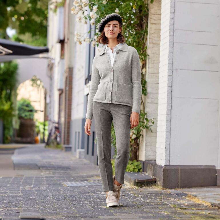Junghans 1954 Feel-Good-Cardigan Frau in grauem Feel-Good-Cardigan mit Beret, steht in einer Stadtstraße.