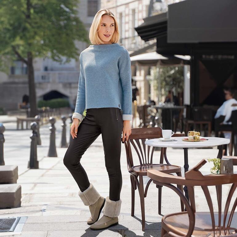 arche Doubleface-Lammfellboots Frau in hellblauem Pullover und Lammfellboots sitzt im Freien.