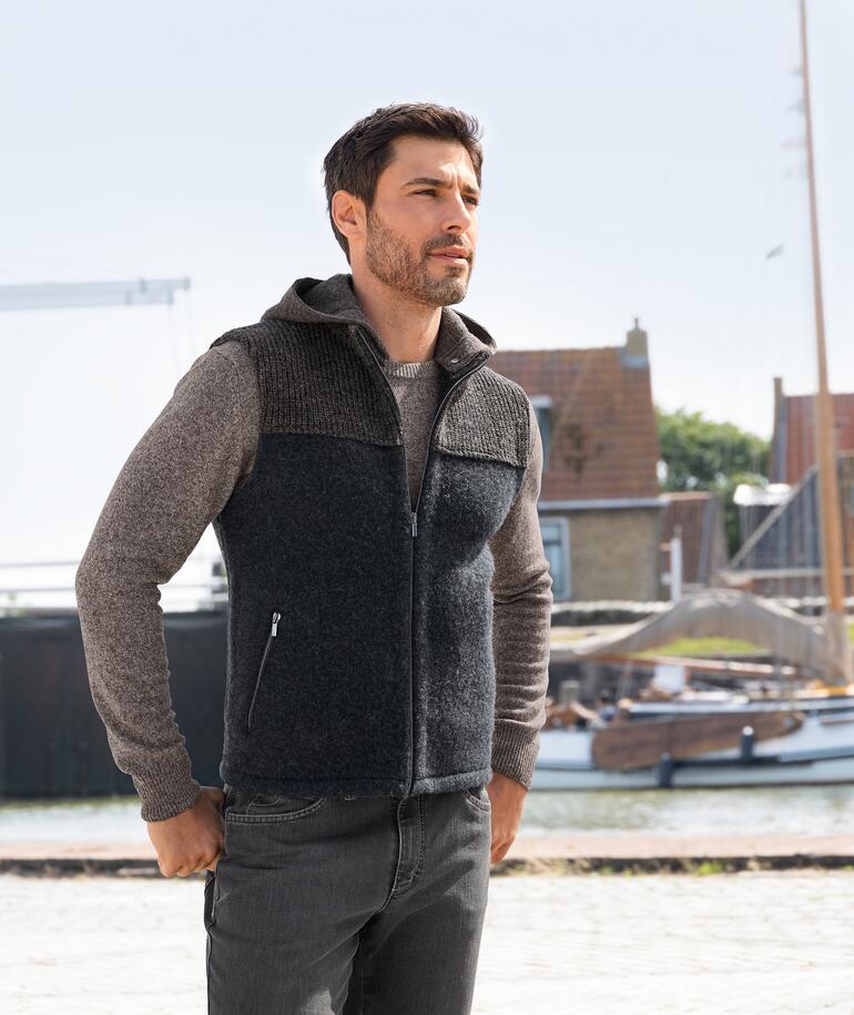 Mann in stapf Walk-Kapuzenweste, Blick zur Seite, Hafen im Hintergrund.