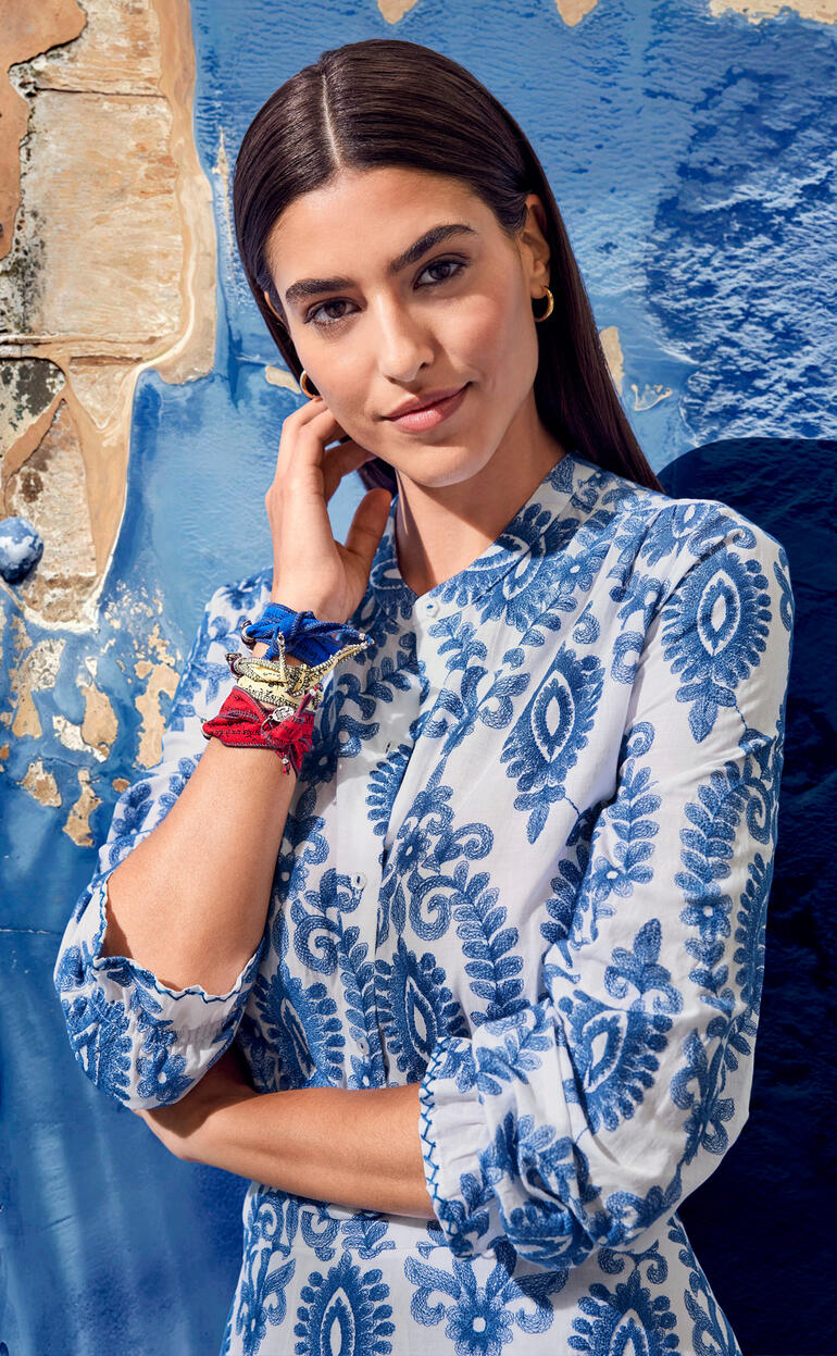 Bluse und Rock Nahaufnahme von einer Frau mit blauem Musterkleid, lächelt in die Kamera.