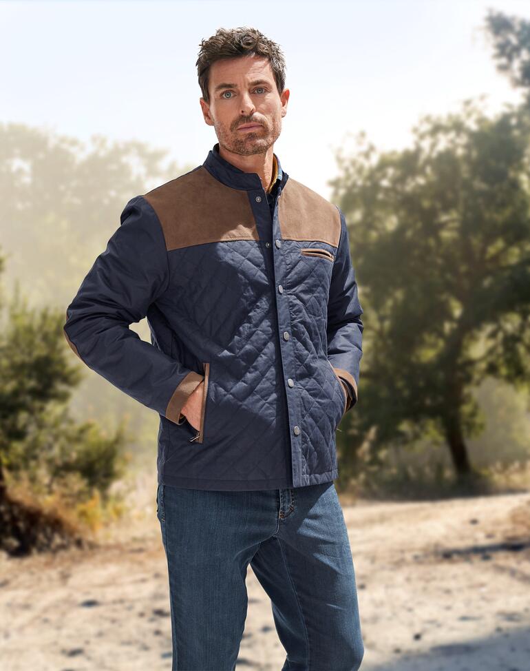 Mann in Leinen-Country-Jacke schaut ernst in die Kamera.