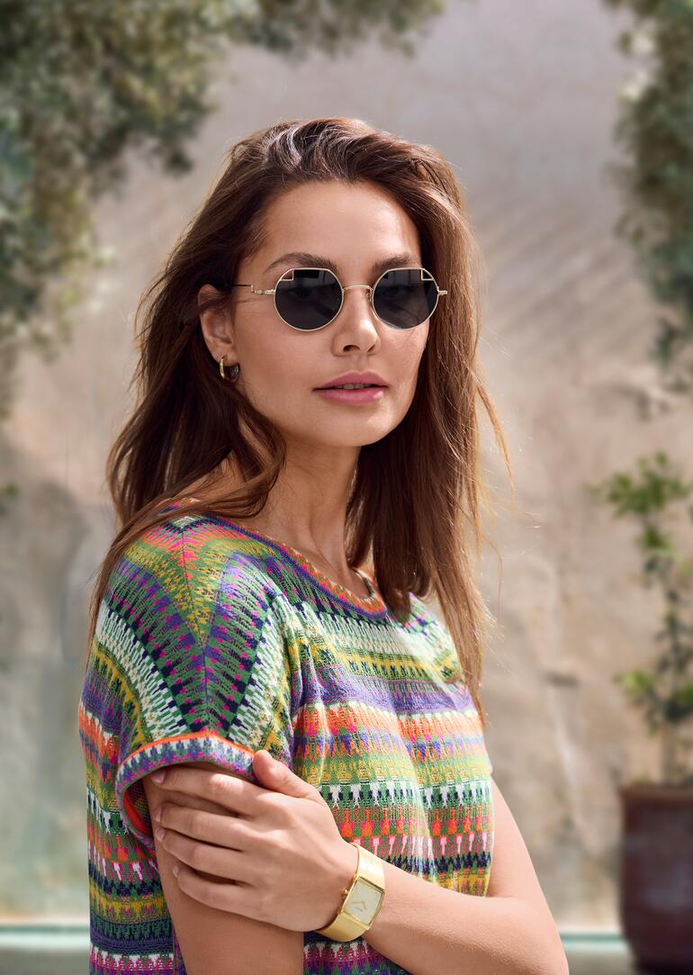 Frau trägt runde John Lennon Damen-Sonnenbrille und ein buntes Oberteil