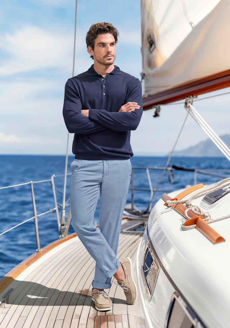 Beige Mann in einem Bootsoutfit auf einem Boot mit maritimem Hintergrund.
