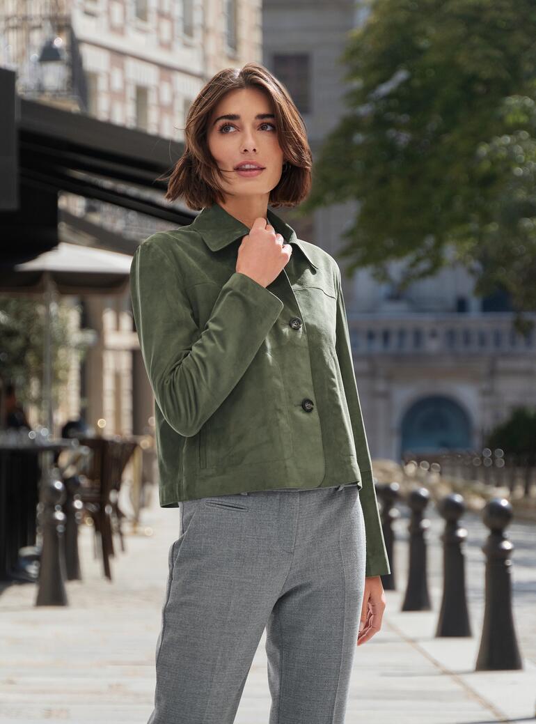 Dame in grüner Lederjacke mit Jeans in einem urbanen Umfeld