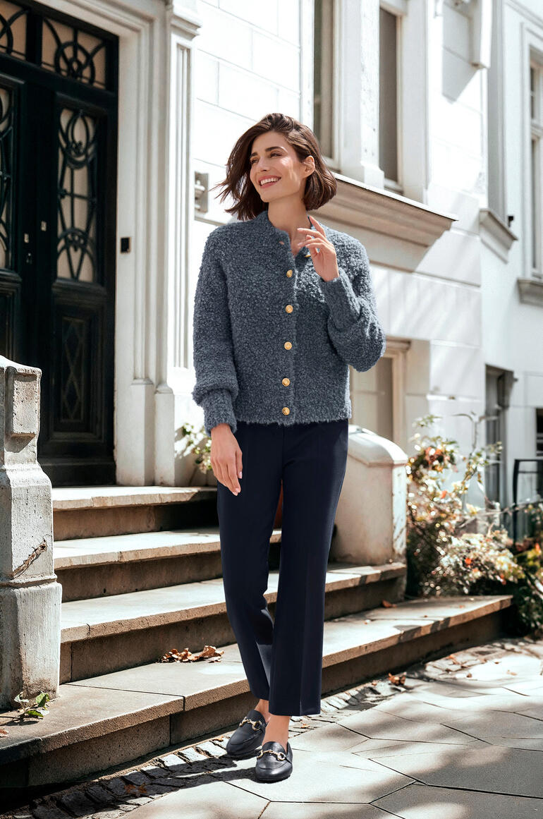 Junghans 1954 Alpaka-Bouclé-Strickjacke Frau in grauer Alpaka-Bouclé-Strickjacke auf Treppe.