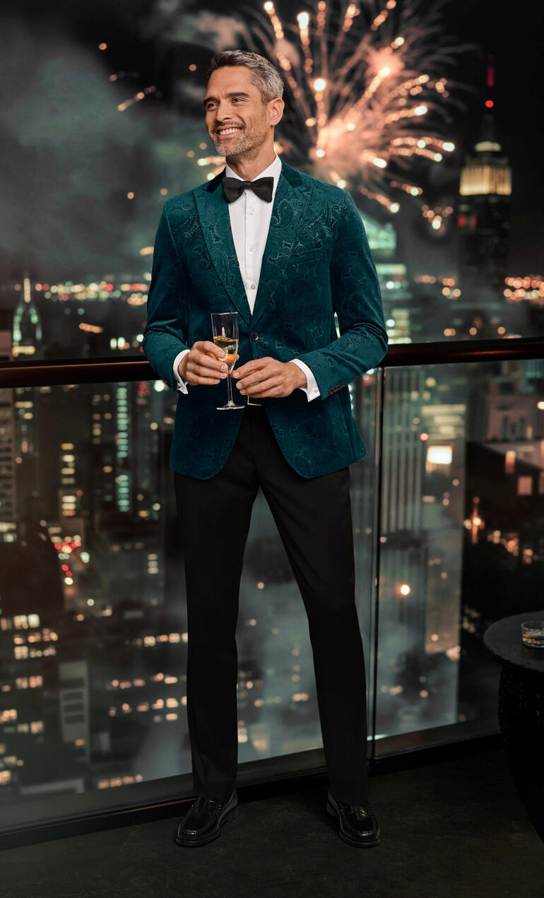 Carl Gross Paisley-Samtsakko Mann im grünen Paisley-Samtsakko mit Blick auf die Stadt.