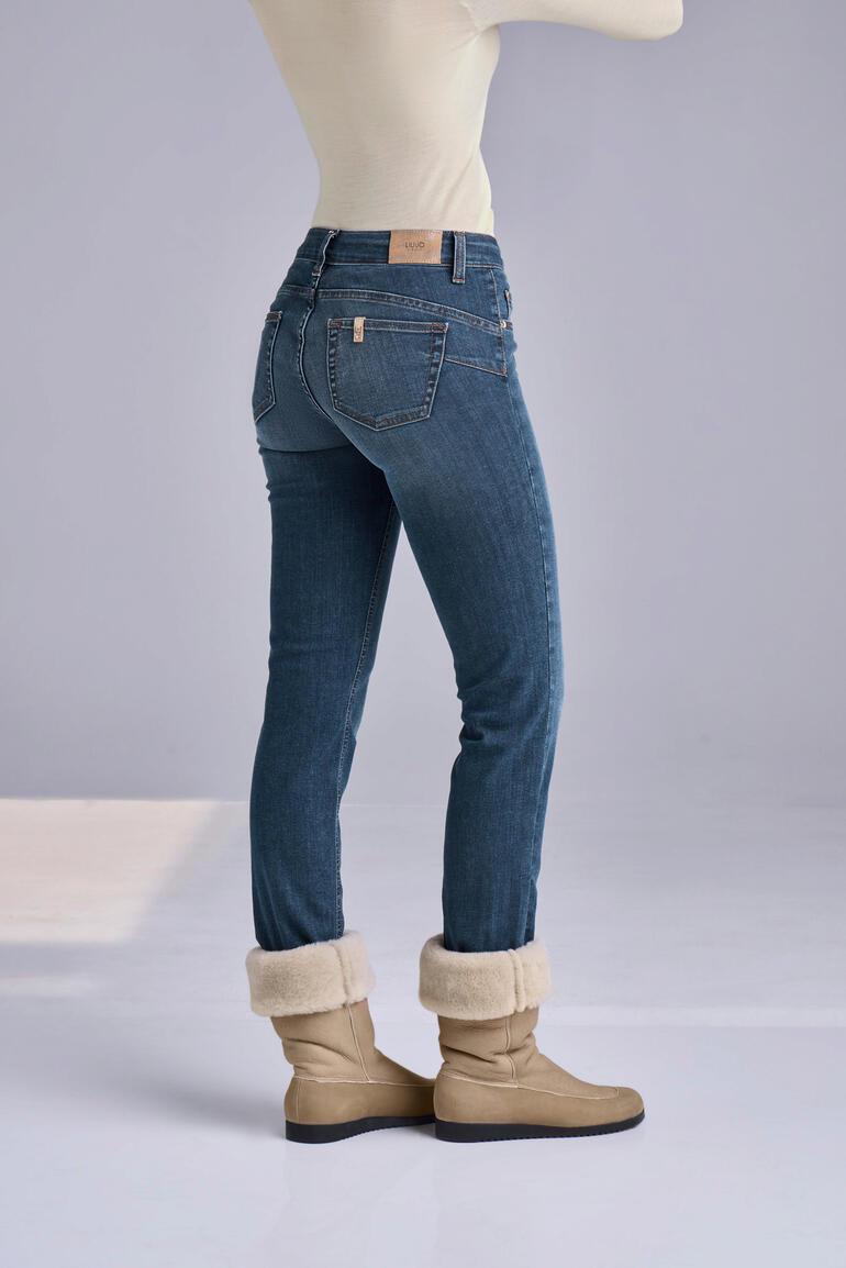 Liu Jo Bottom up-Röhren-Jeans „Better Denim“ Frau zeigt die Rückansicht in blauen Jeans und braunen Winterstiefeln.