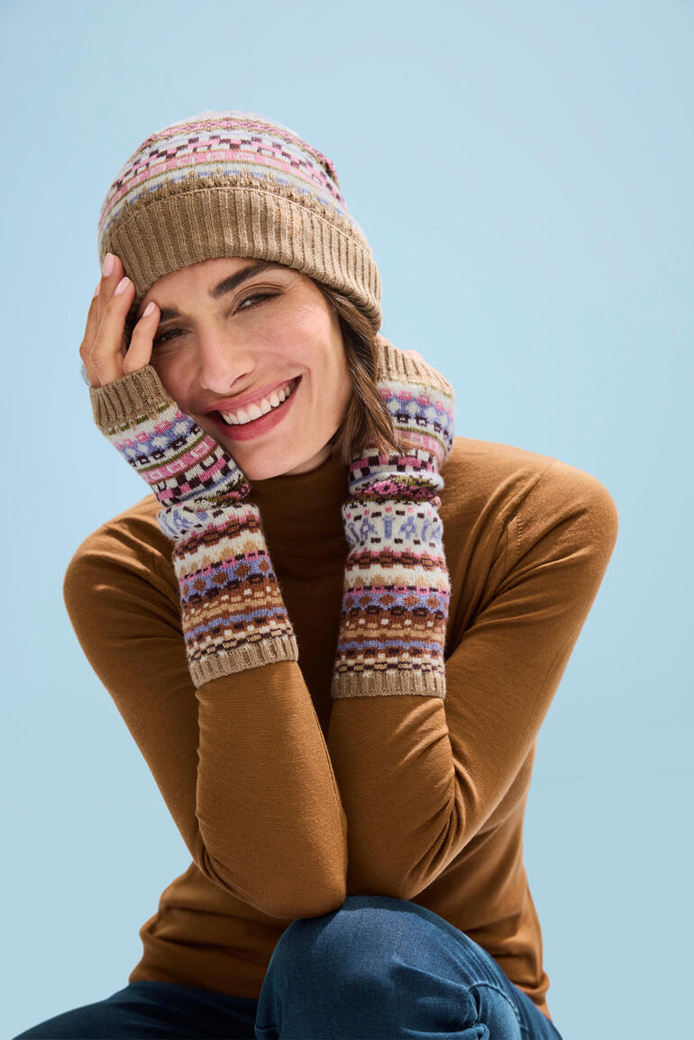 Mütze und Stulpen Frau trägt Jacquard-Mütze und Stulpen, lächelt in winterlicher Umgebung.