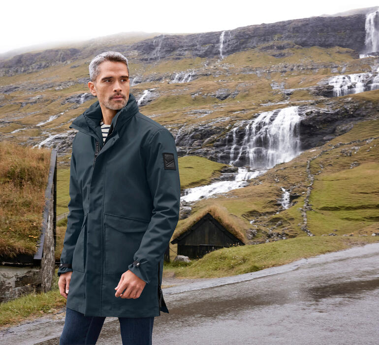 Navy Mann in 3-in-1-Allwetter-Parka in einer Berglandschaft.