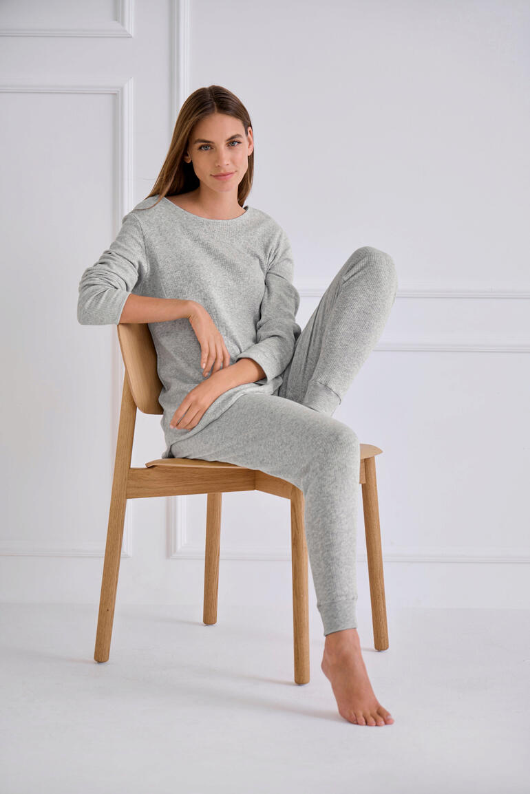 Termotex Pyjama Frau in grauem Pyjama sitzt auf einem Stuhl
