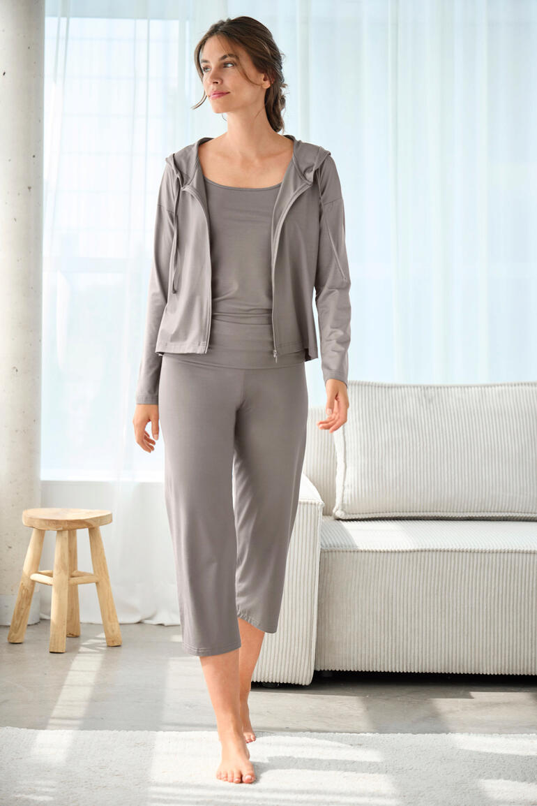 Frau in kompletter Loungewear-Kombination steht in einer hellen Umgebung.