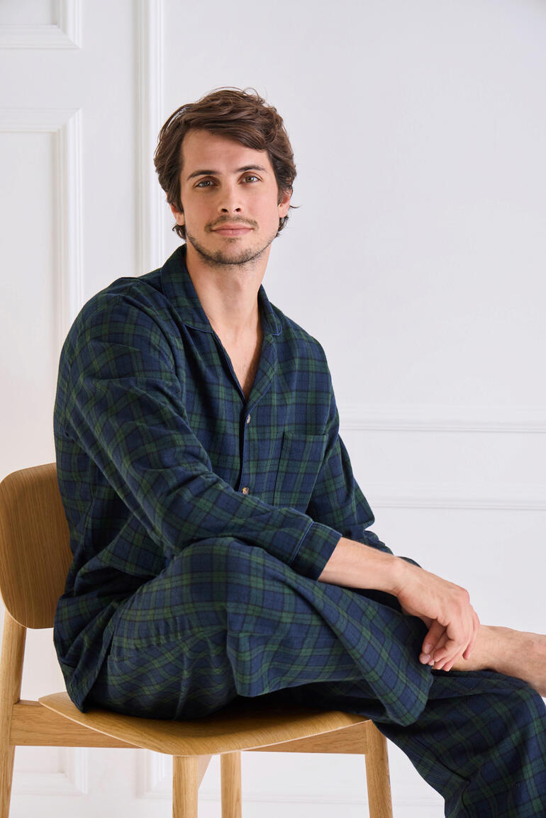 Grandfather-Flanell-Pyjama Mann in kariertem Flanellpyjama, sitzt auf einen Stuhl.