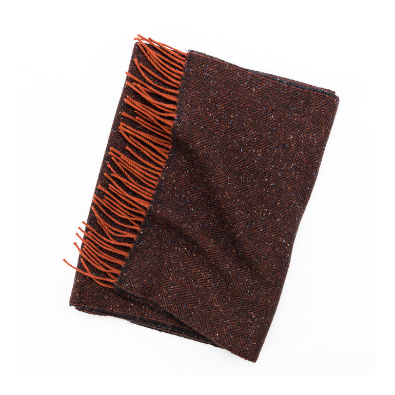 Tweed-Schal Tweed-Schal in dunkelorange und braun, auf einem Tisch gelegt.