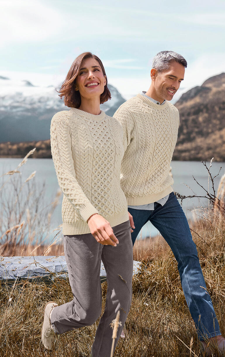 Merino-Aran-Pullover Paar in Merino-Aran-Pullis bei einem Spaziergang mit Naturhintergrund