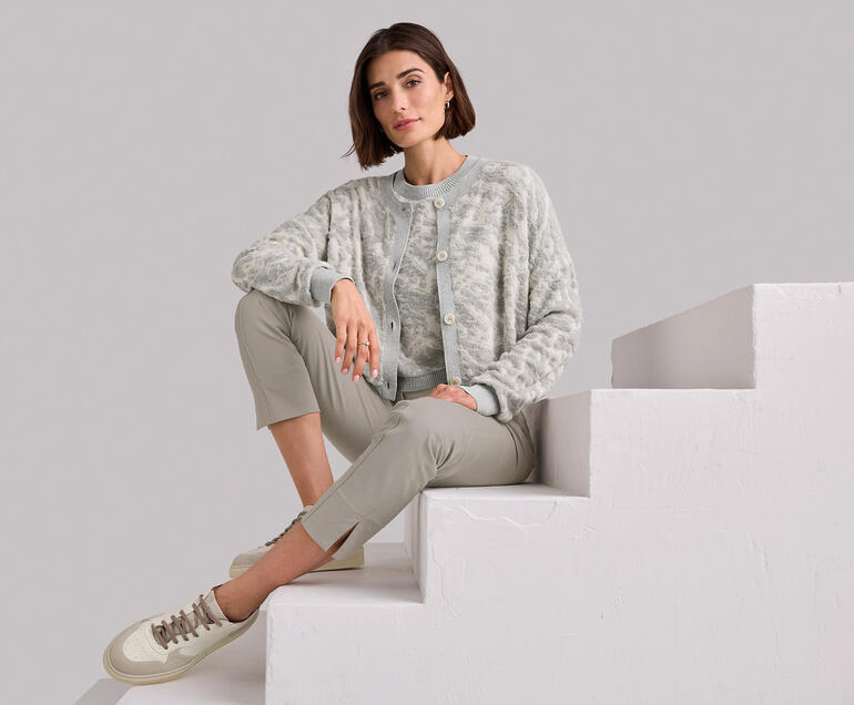 Ducanero® Basic-Edel-Sneaker Frau sitzt auf einer Treppe, trägt ein graues 3D-Jacquard-Twinset.
