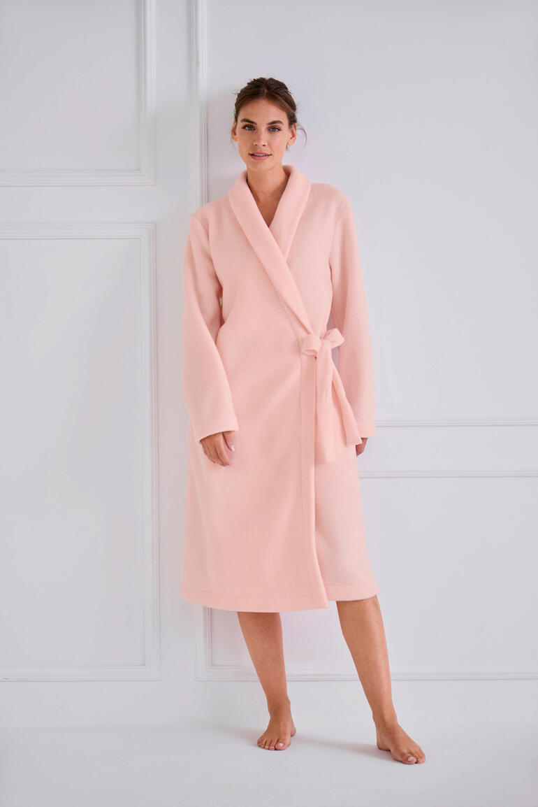 le chat Fleece-Morgenmantel Frau in einem rosa Fleece-Morgenmantel, steht in voller Länge.