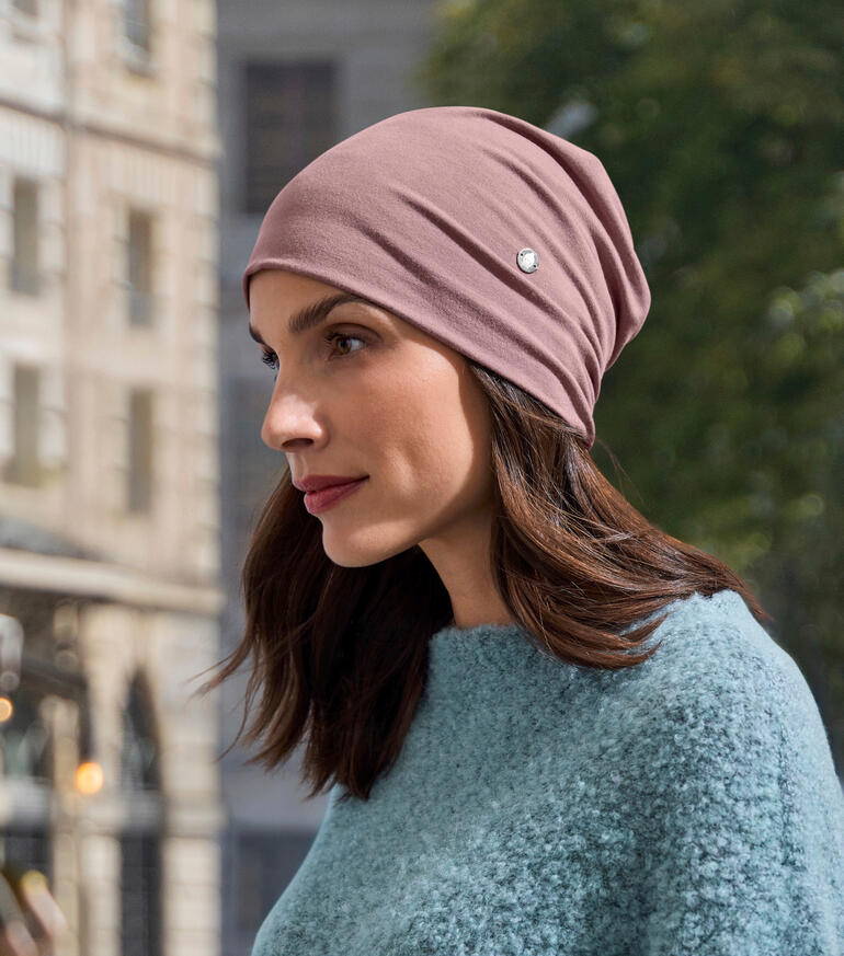 Bambus-Beanie in rosa, getragen von einer Frau in einem blauen Pullover.
