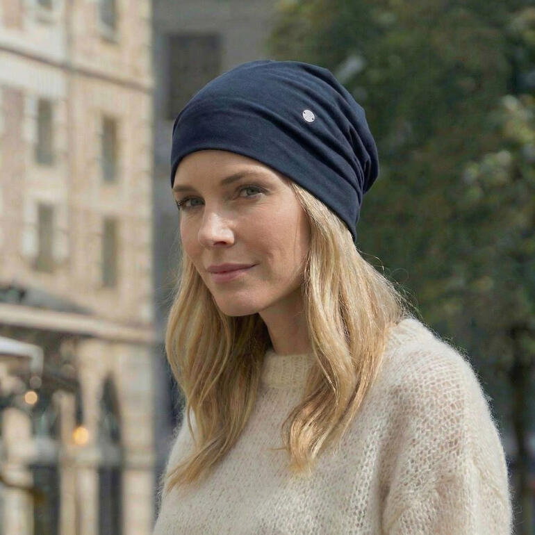 Dame trägt dunkelblauen Ganzjahres-Beanie mit dekorativem Logo.
