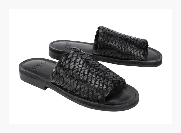 Zwei schwarze Flecht-Slides von Cano auf weißem Hintergrund.