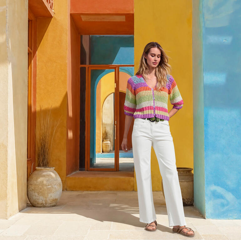 RAPHAELA BY BRAX Zauberbund-Wide-leg-Pants Frau in einem bunten Seiden-Grobstrick-Cardigan vor buntem Hintergrund