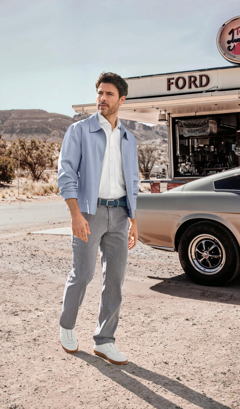 Mann in hellblauem Sommerblouson, steht vor einem Diner.