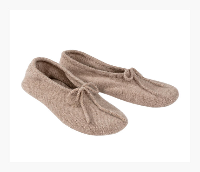 Zwei Kaschmir-Reisehausschuhe in hellem beige nebeneinander.