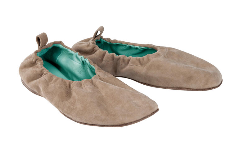 Braune Elastik-Ballerinas auf weißem Hintergrund, weich und flexibel.