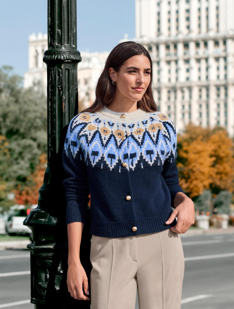 Frau trägt einen JH1954 Couture-Norweger-Cardigan mit Farbmustern