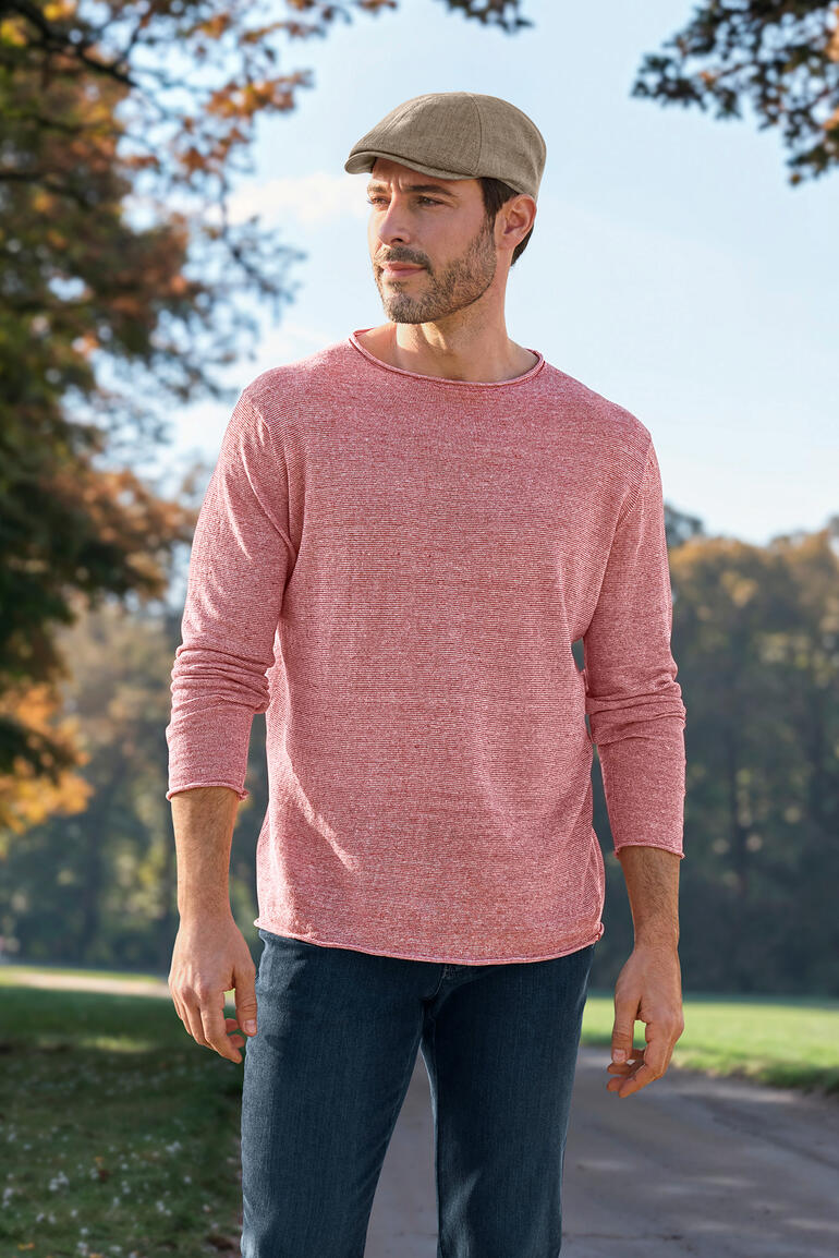 Taupe Mann in roten Pullover mit Longsleeve und Mütze in der Natur.